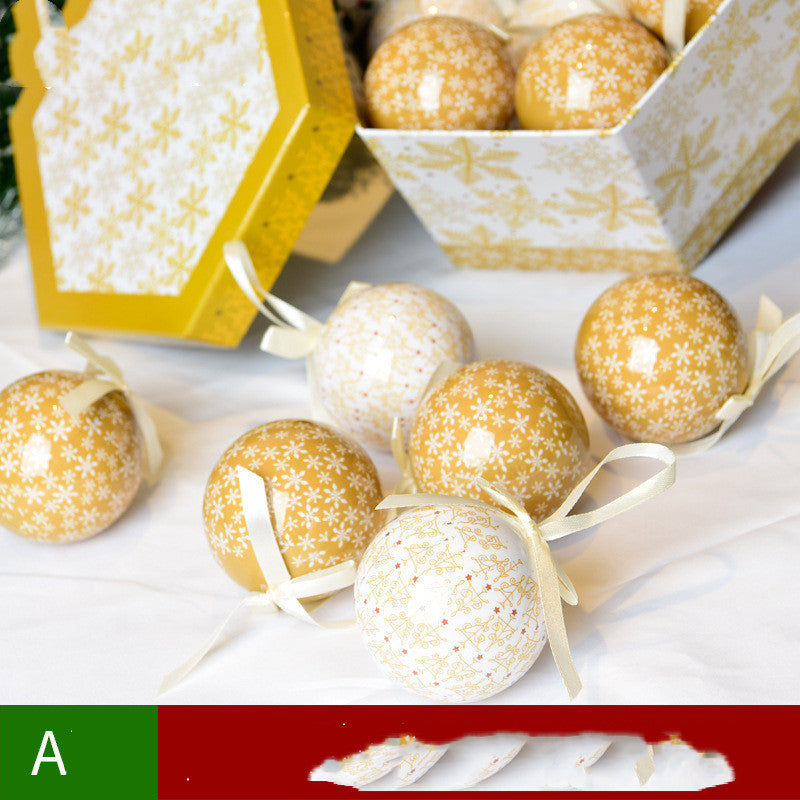 Gold and white Christmas baubles with snowflake patterns and ribbons, next to decorative gift box