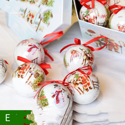 White ceramic Christmas ornaments with snowman and Santa designs, red ribbons in a festive gift box
