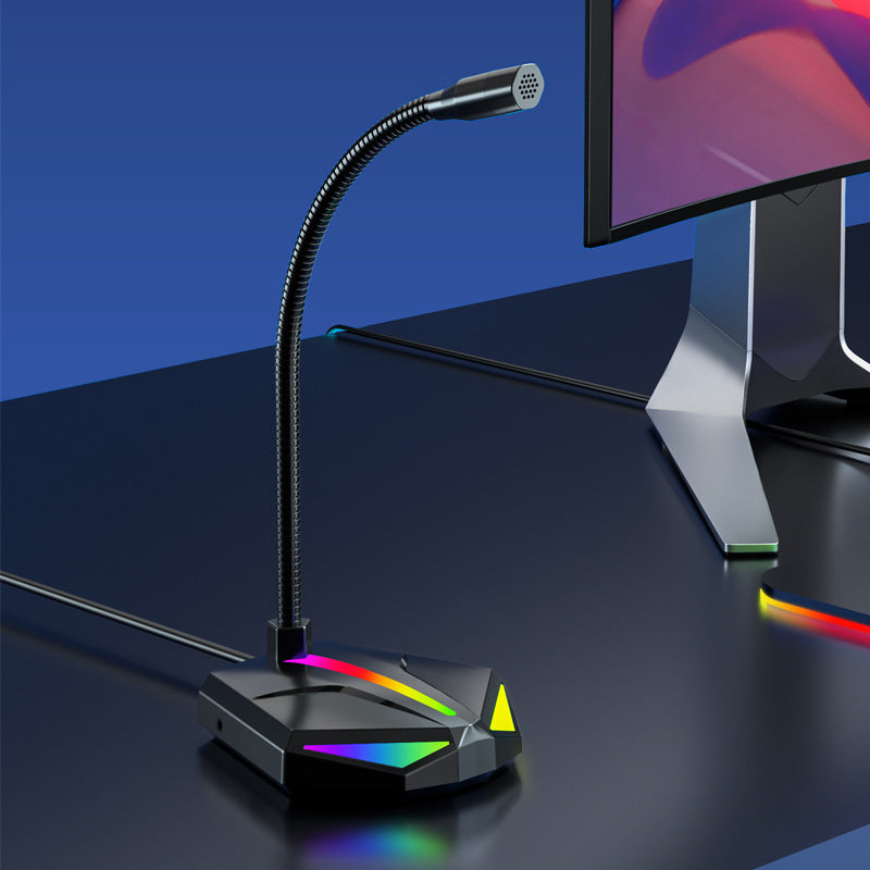 Black USB gaming microphone with flexible gooseneck and RGB lighting on base next to gaming monitor