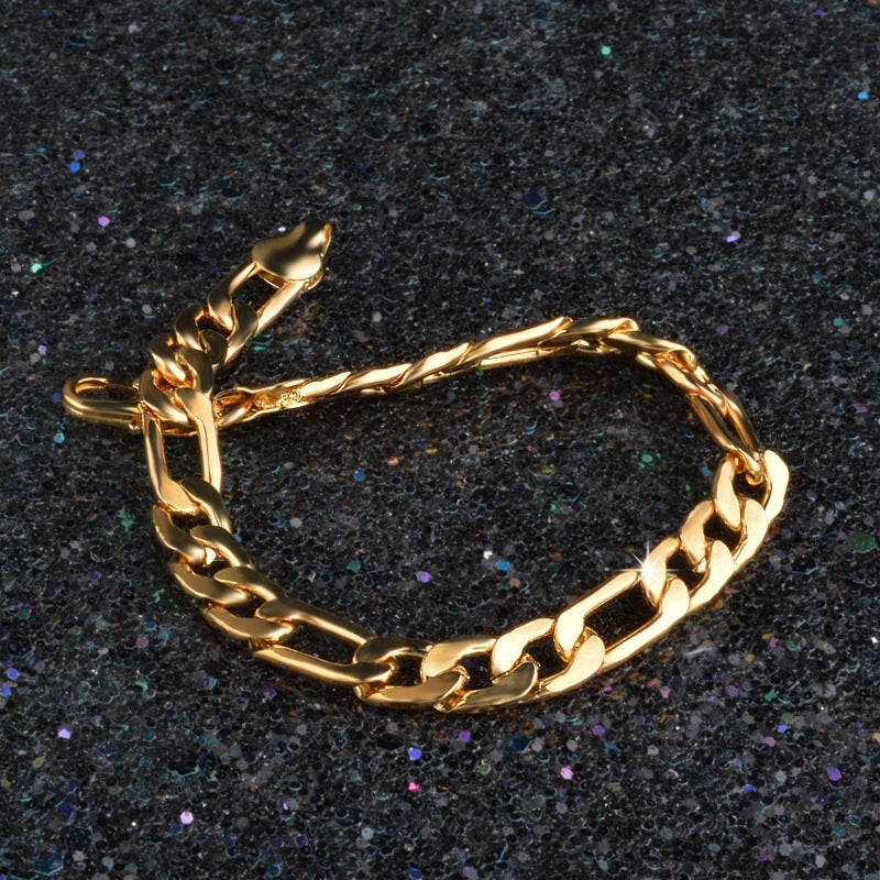 Gold tone Figaro chain bracelet with 8mm links on a dark glittery surface