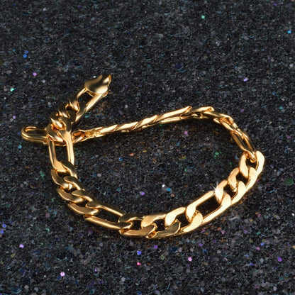Gold tone Figaro chain bracelet with 8mm links on a dark glittery surface
