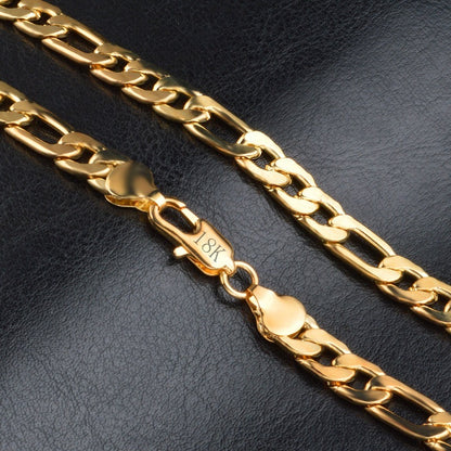 18K gold Figaro chain bracelet with polished links on black leather surface