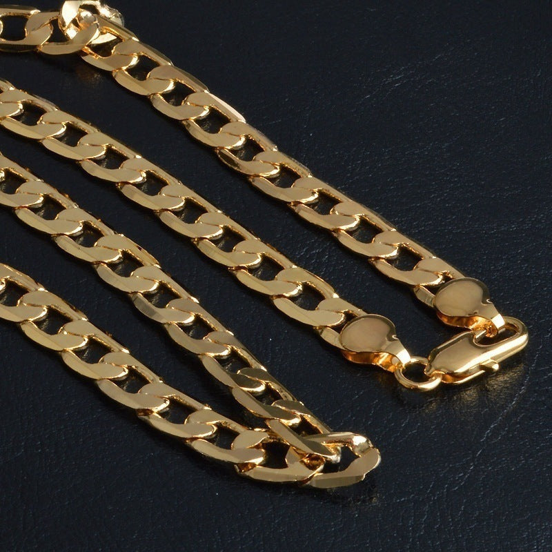 Close-up of shiny gold figaro chain bracelet with a box clasp on black textured surface