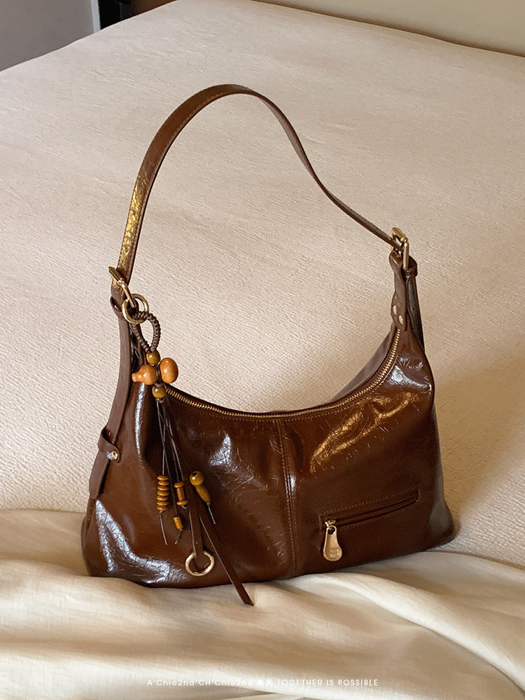 Sugar brown women's large PU leather tote bag with wooden bead tassel on cream fabric background