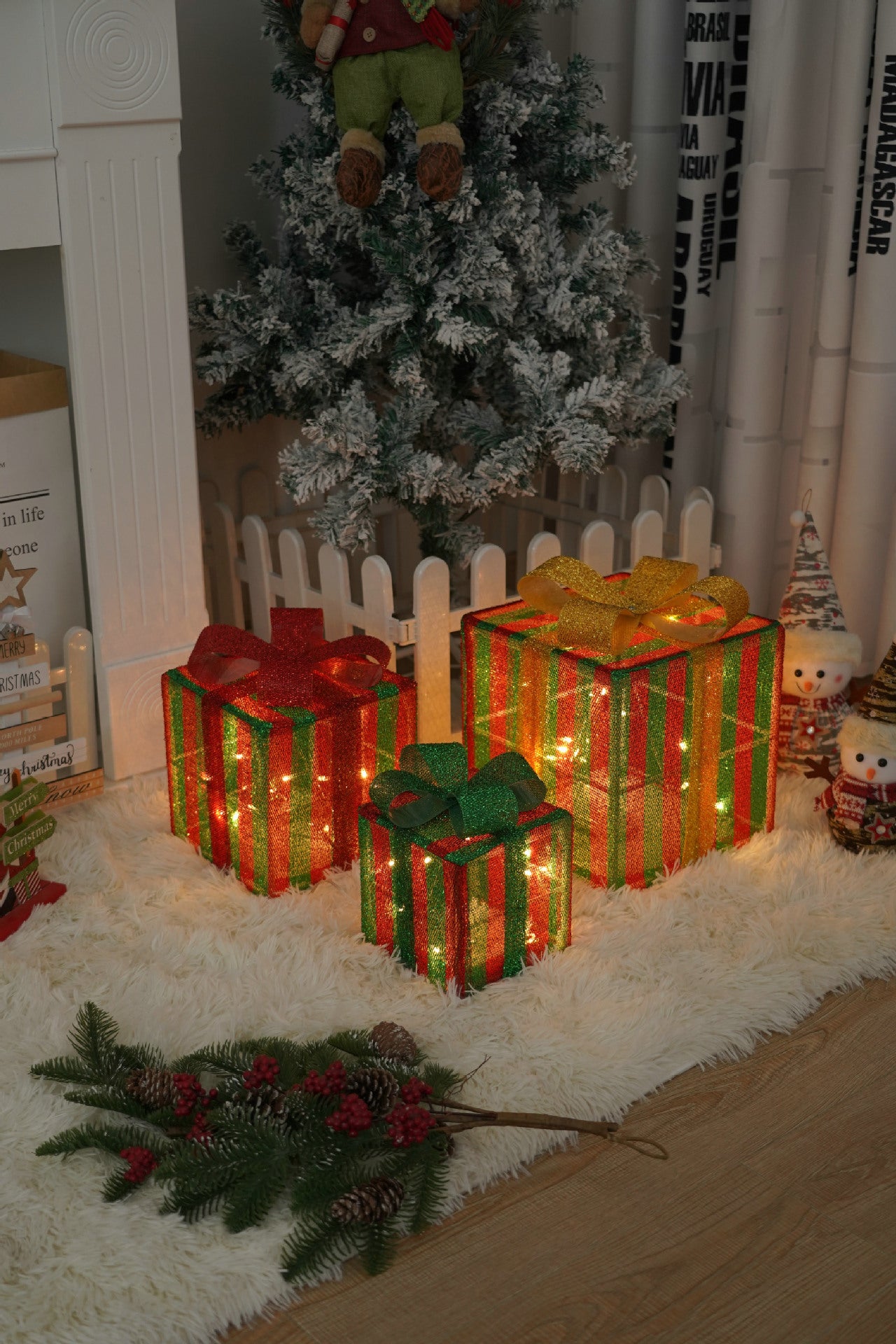 Three glowing Christmas gift boxes with red, green, and gold stripes under a snowy tree with festive décor