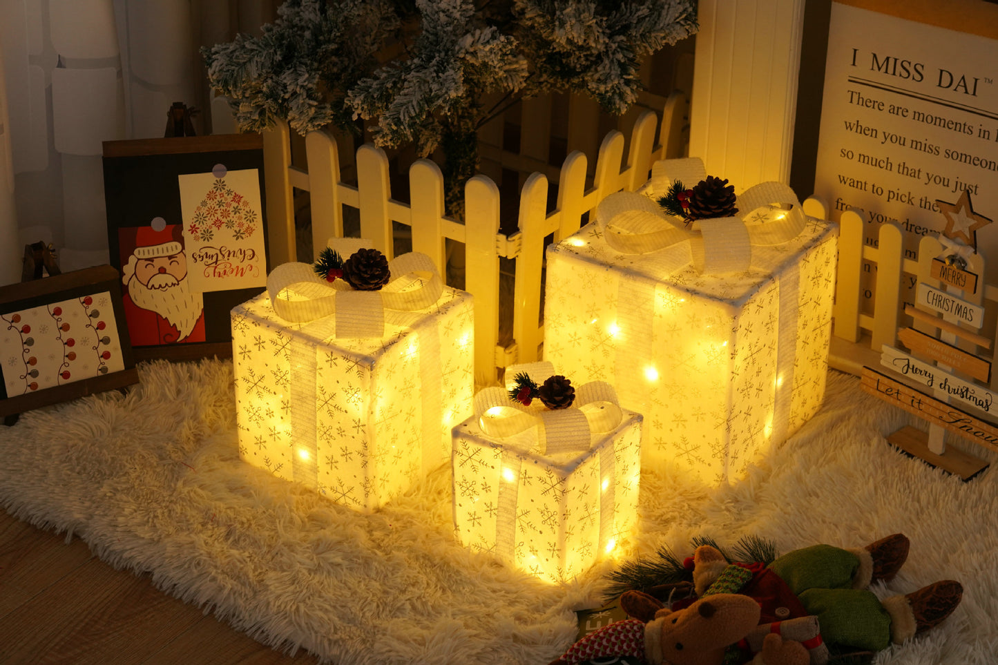 Three glowing white Christmas gift boxes with snowflake patterns and pinecone decorations on a fluffy rug