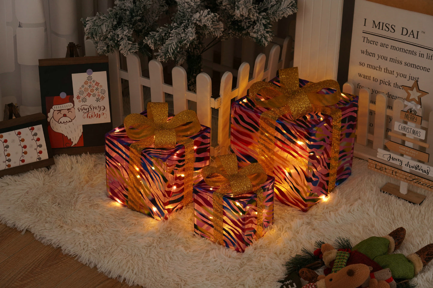 Three colorful zebra-striped Christmas gift boxes with gold ribbon bows and warm battery-operated lights on a fluffy rug