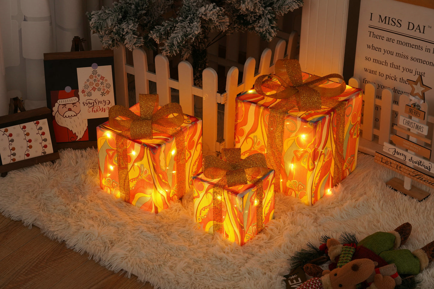 Three glowing Christmas gift boxes with orange paisley patterns and glittery gold ribbons on a fluffy white rug