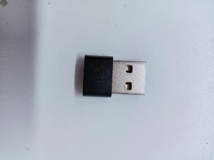 USB Type-A wireless adapter with black plastic housing on white surface