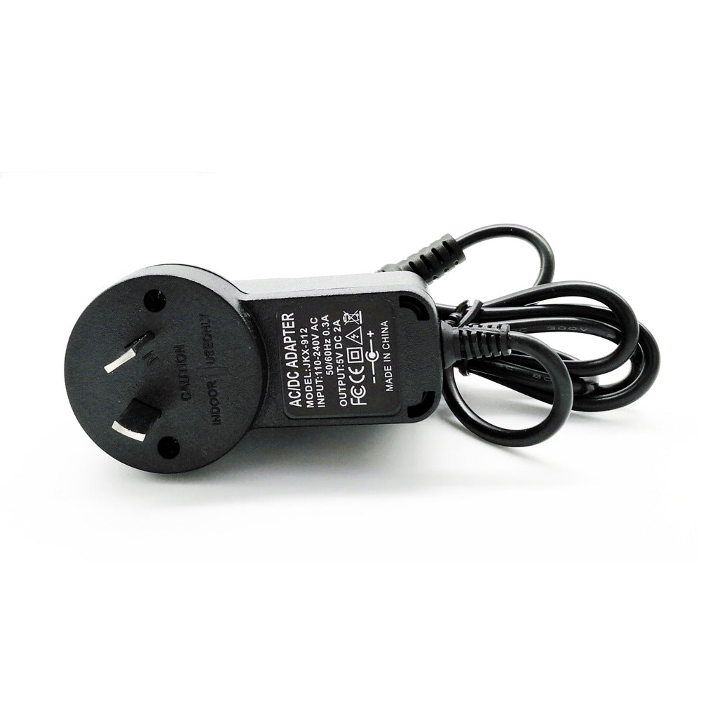 Black AC DC adapter with power plug and coiled cable on white background