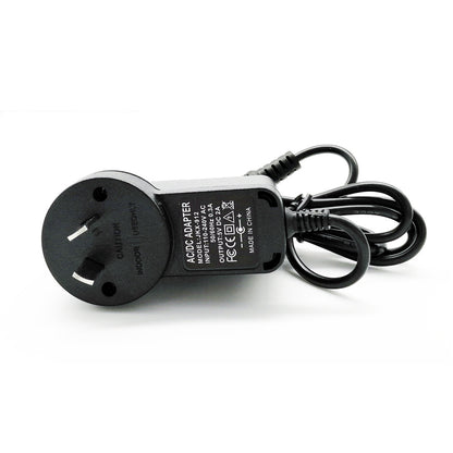 Black AC DC adapter with power plug and coiled cable on white background
