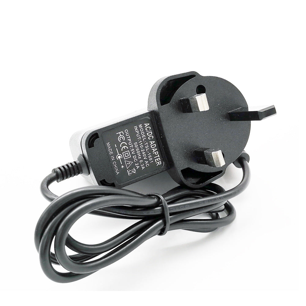 Black UK plug AC/DC adapter with coiled cable for electronic devices on white background