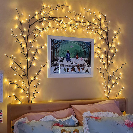 Warm white LED birch vine string lights framing a wall painting above a cozy bed with floral pillows