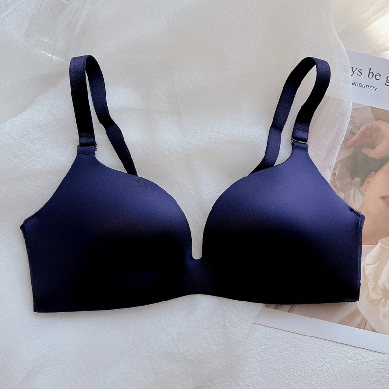 Navy blue wireless push-up bra with thin, adjustable straps on white fabric surface