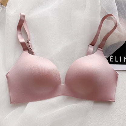 Pink wireless push-up bra with thin seamless cups and adjustable straps on white fabric background