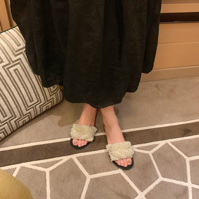 Women wearing white pearl slippers with black soles indoors on patterned carpet