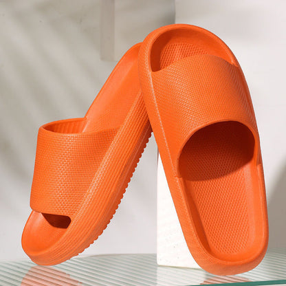 Pair of orange cushioned EVA foam slides with thick soles on reflective surface