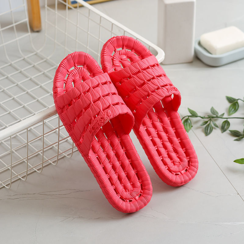 Bright red woven textured slip-on slippers placed on white tiled floor near wire storage basket and soap dish