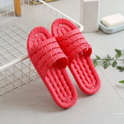 Bright red woven textured slip-on slippers placed on white tiled floor near wire storage basket and soap dish