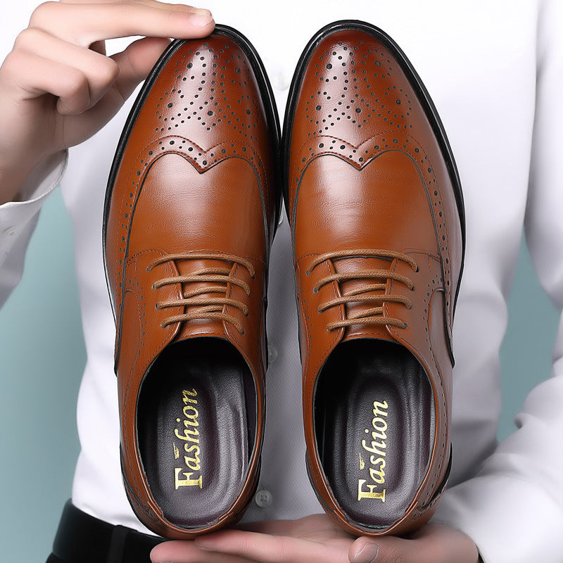 Pair of brown leather men's dress shoes with brogue detailing and lace-up design held by person in white shirt