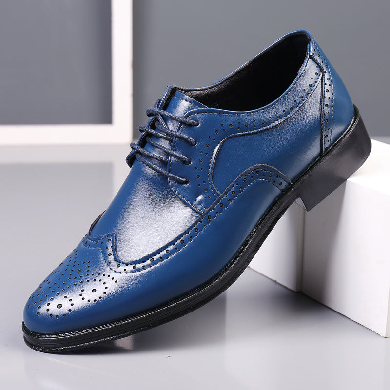 blue men's leather wingtip dress shoe with black sole and brogue perforations on grey surface
