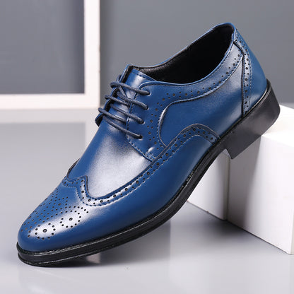 blue men's leather wingtip dress shoe with black sole and brogue perforations on grey surface