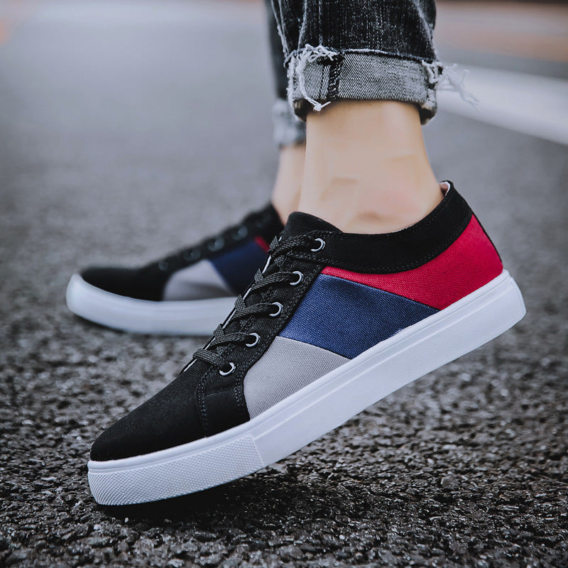 Close-up of casual men's sneakers with black, red, blue, and gray canvas on asphalt surface
