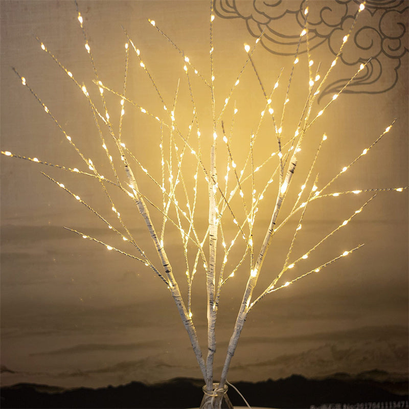 White birch tree branches decorated with warm white LED string lights in a vase, indoor decorative lighting