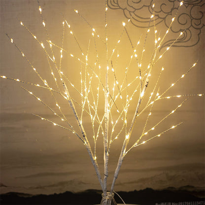 White birch tree branches decorated with warm white LED string lights in a vase, indoor decorative lighting
