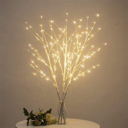 White birch tree LED decorative lights in clear vase on table with flowers, warm white glow