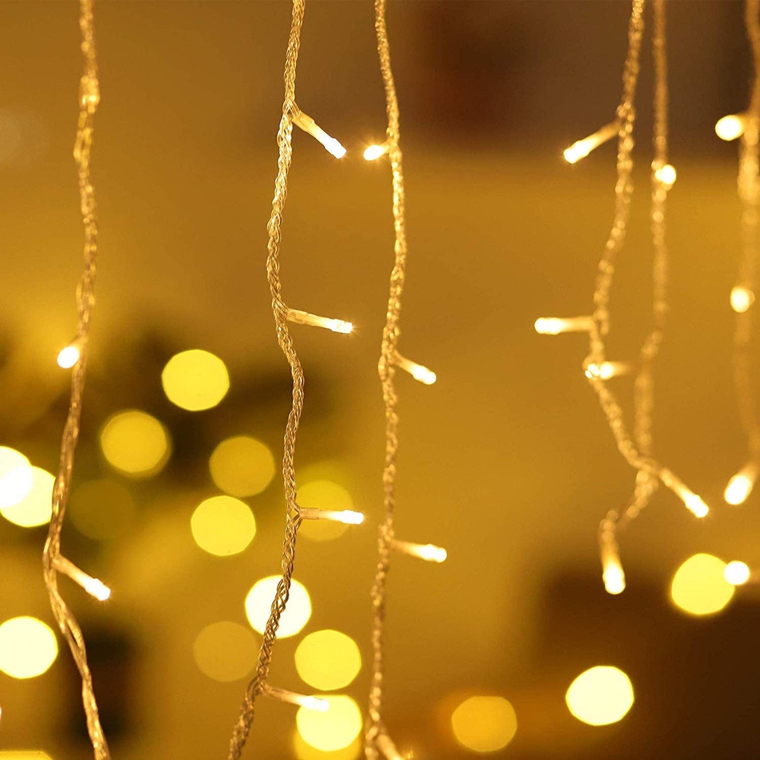 Warm white LED icicle string lights glowing softly with blurred yellow bokeh background