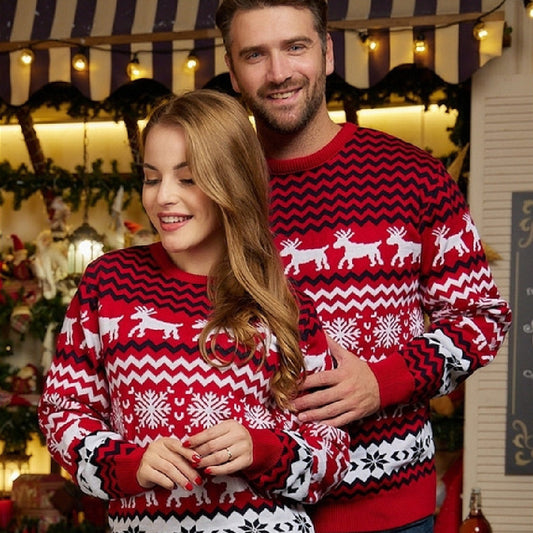 Couple wearing matching red and white Christmas sweaters with reindeer and snowflake patterns in festive setting