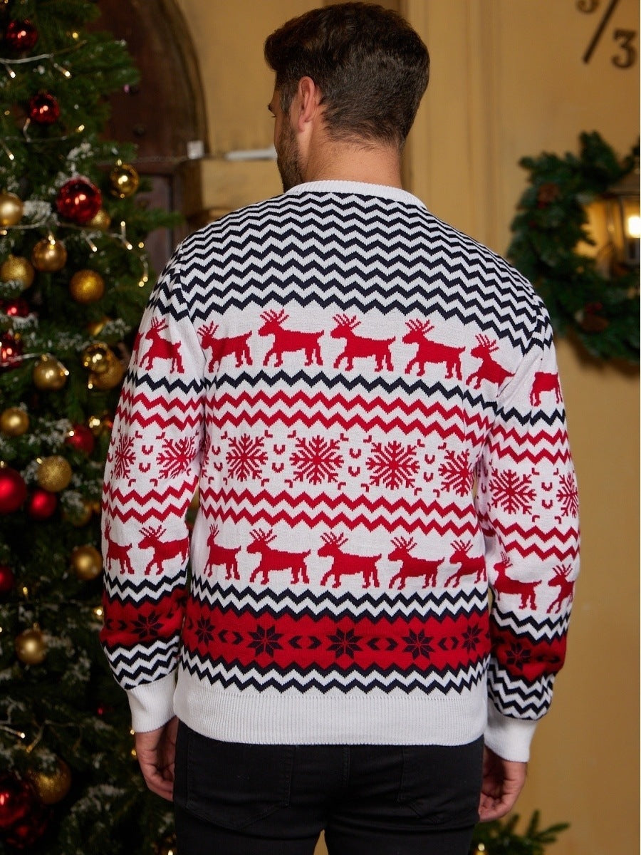 Man wearing white Christmas sweater with red reindeer and snowflake patterns by decorated tree