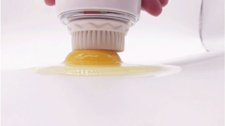 Ultrasonic electric face washer with white bristles cleaning a sticky yellow substance on white surface