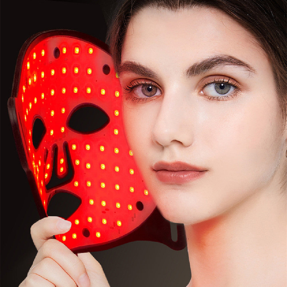Young woman holding red LED light therapy face mask for skin rejuvenation and brightening