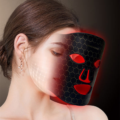 Woman wearing a black LED skin rejuvenation mask with red light and honeycomb pattern