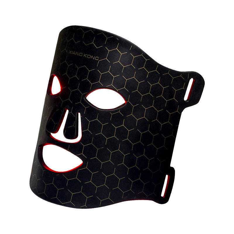 Black LED skin rejuvenation mask with hexagonal pattern and red light glowing through facial openings
