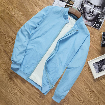 Light blue men's lightweight nylon sun protection jacket on wooden surface with magazine and camera