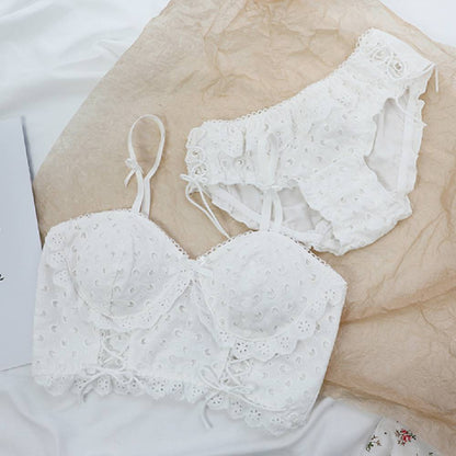 White lace cotton bra and matching high-waist panties set laid on beige fabric
