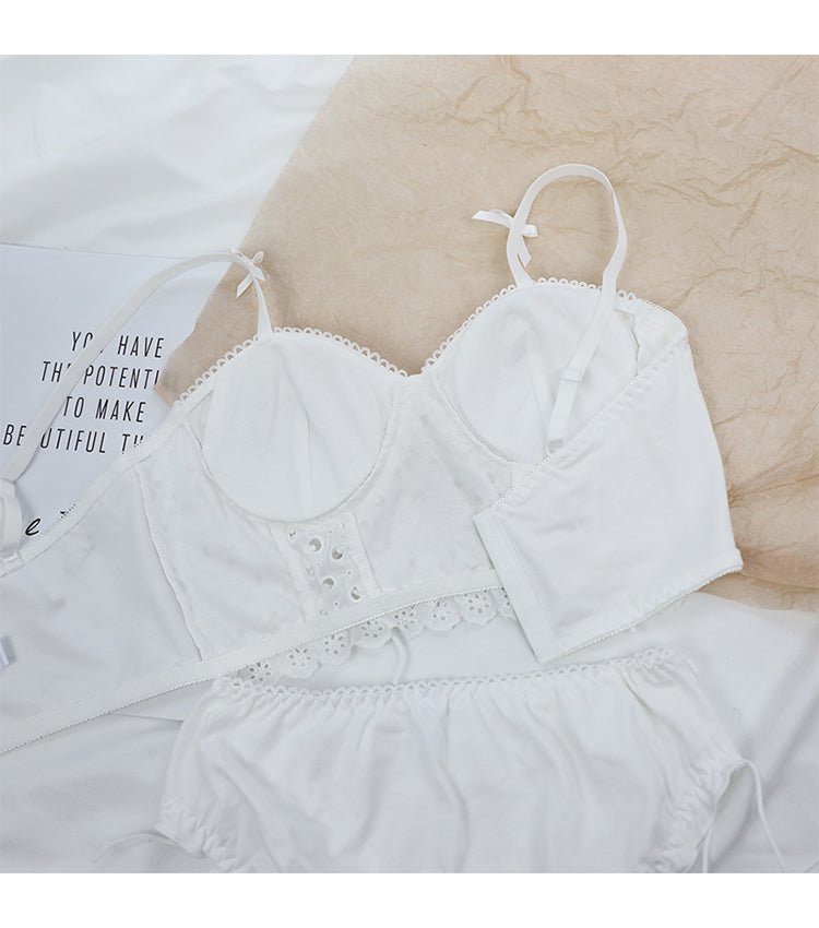 White lace cotton bra set with adjustable straps and matching white bottoms on beige and white background