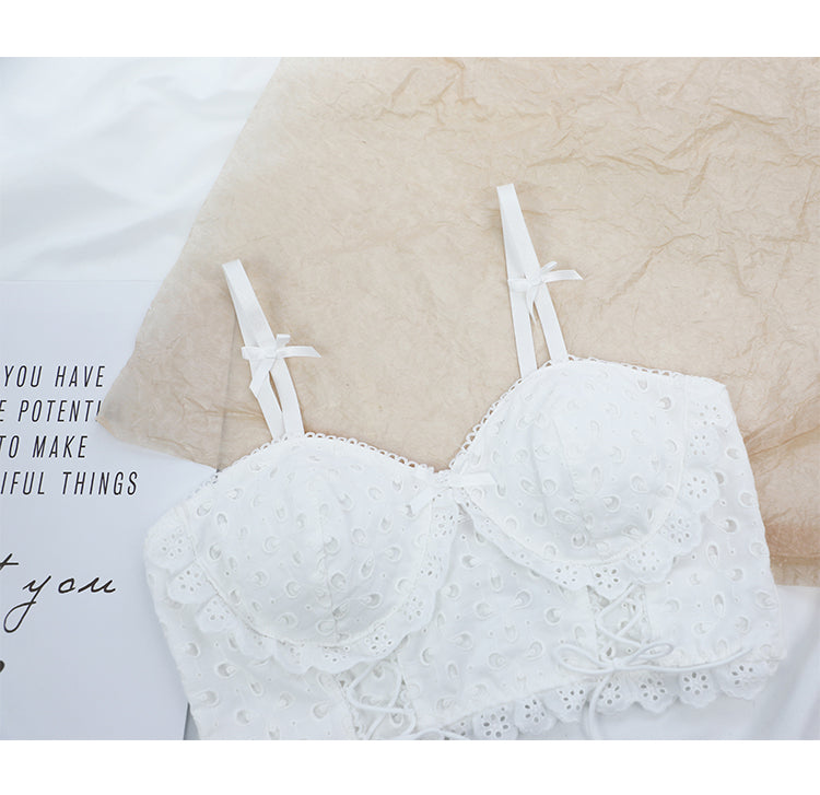 White lace cotton bra with eyelet embroidery and double shoulder straps on crumpled beige paper