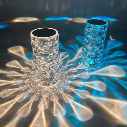 Two crystal glass vases casting intricate light and blue reflections on a reflective surface