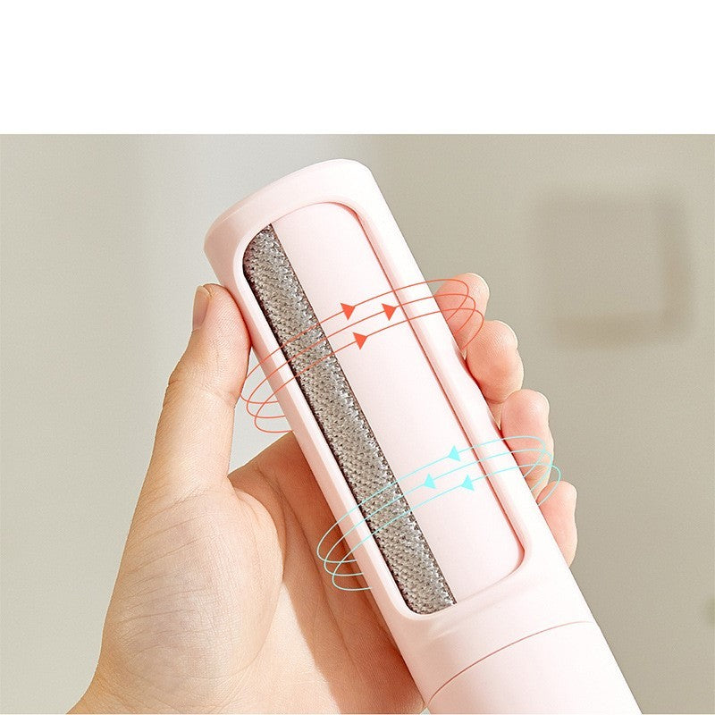 Hand holding a pink reusable pet hair remover brush with textured cleaning surface and arrows indicating self-cleaning action