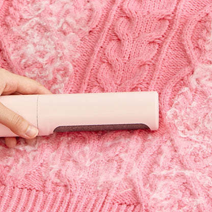 Hand using a pink self-cleaning pet hair remover brush on a pink knitted sweater with pet hair