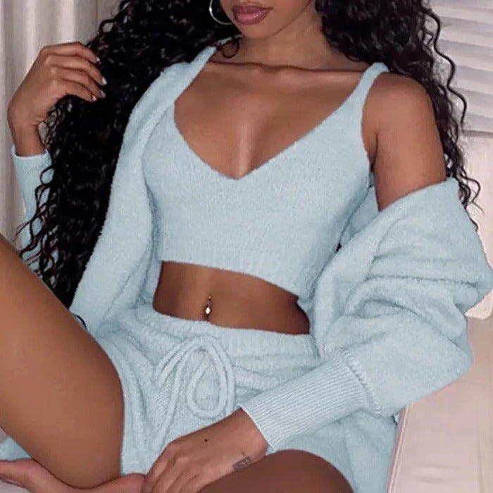 Woman wearing light blue velvet pajama set with crop tank top, drawstring shorts, and matching cardigan