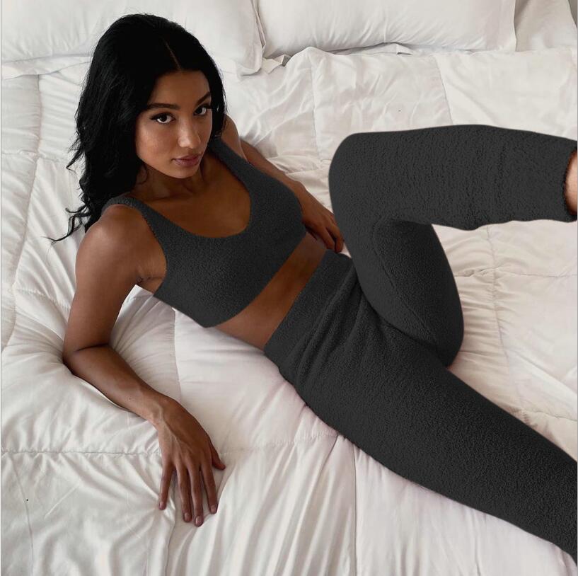woman reclining on white bed wearing black fuzzy crop top and matching high-waisted pants loungewear