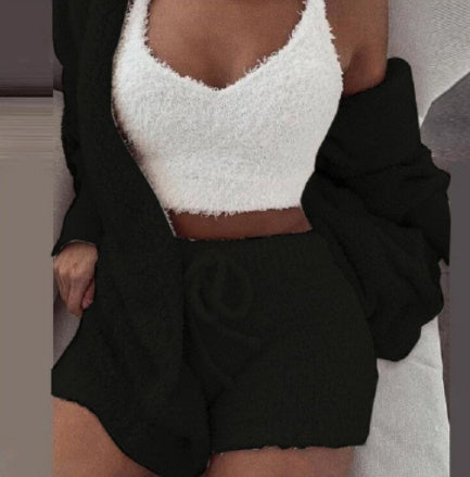 woman wearing cozy white fuzzy crop top and black drawstring shorts loungewear set with oversized black cardigan