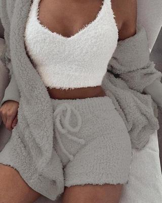 Woman wearing cozy white velvet pajama set with crop top, drawstring shorts, and matching cardigan