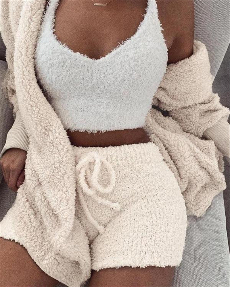 Woman wearing cozy white velvet pajama set with crop top, drawstring shorts, and fluffy cardigan