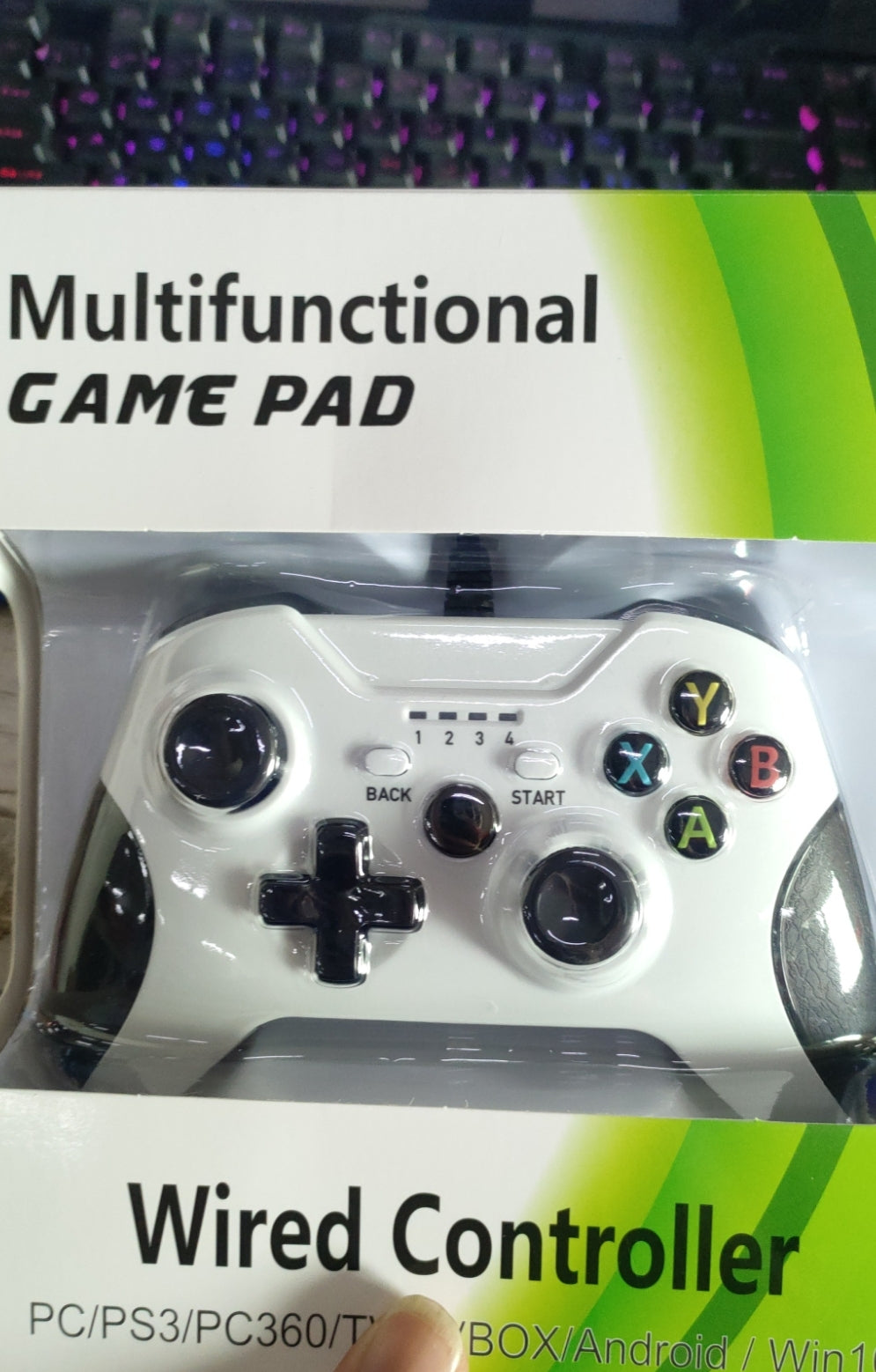 White multifunctional wired gamepad with black buttons and colored ABXY keys in green packaging